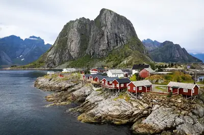 Röda rorbuer vid vattnet och branta fjäll i Lofoten